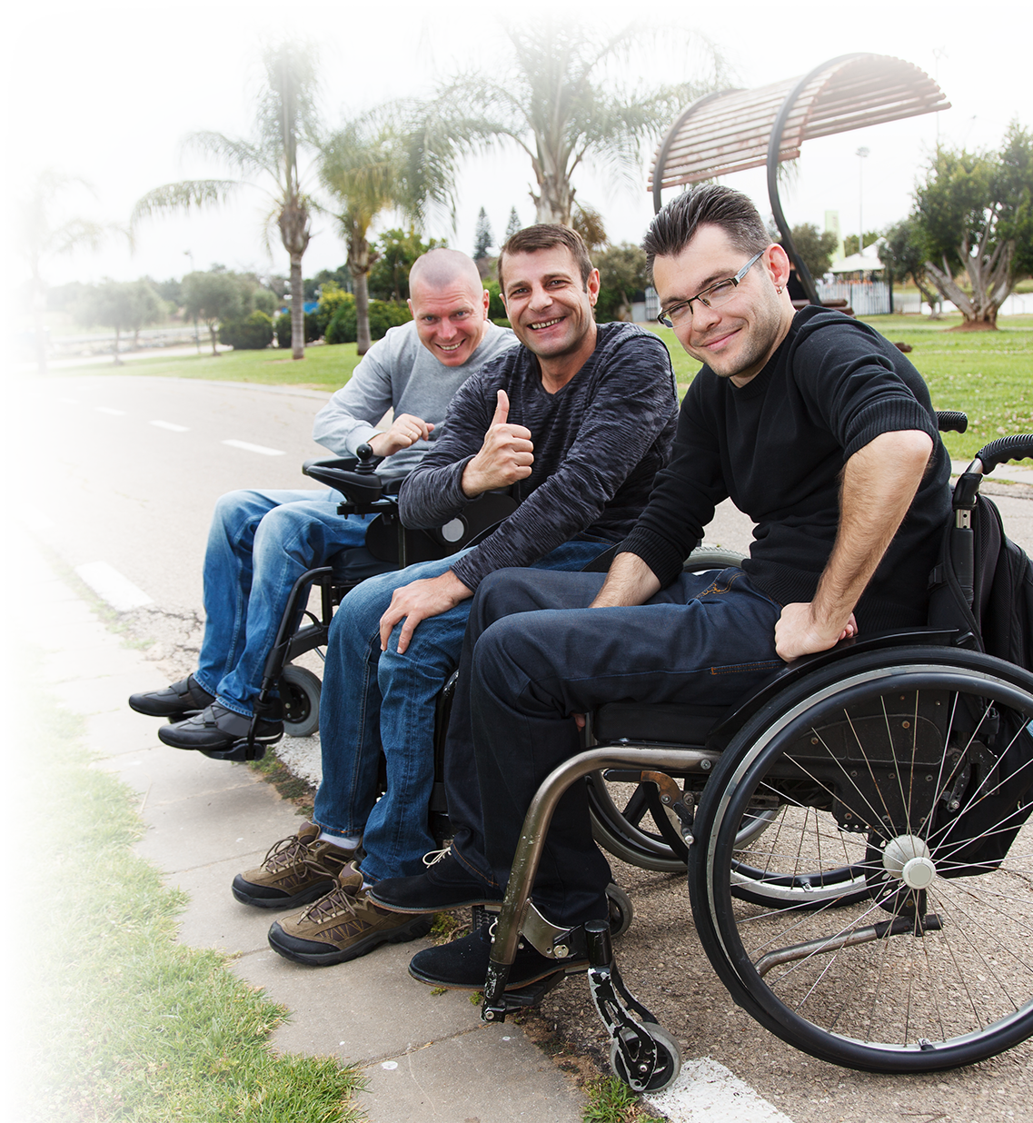 Three men together at a park in their wheelchairs.